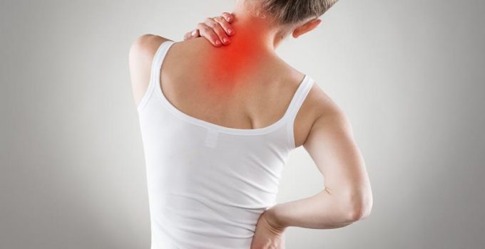 a woman with one hand on her neck and one hand on her lower back showing trigger points in red in Grand Rapids, MI