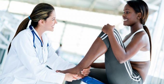 a woman physician smiling at patient helping with foot pain relief in Grand Rapids, MI