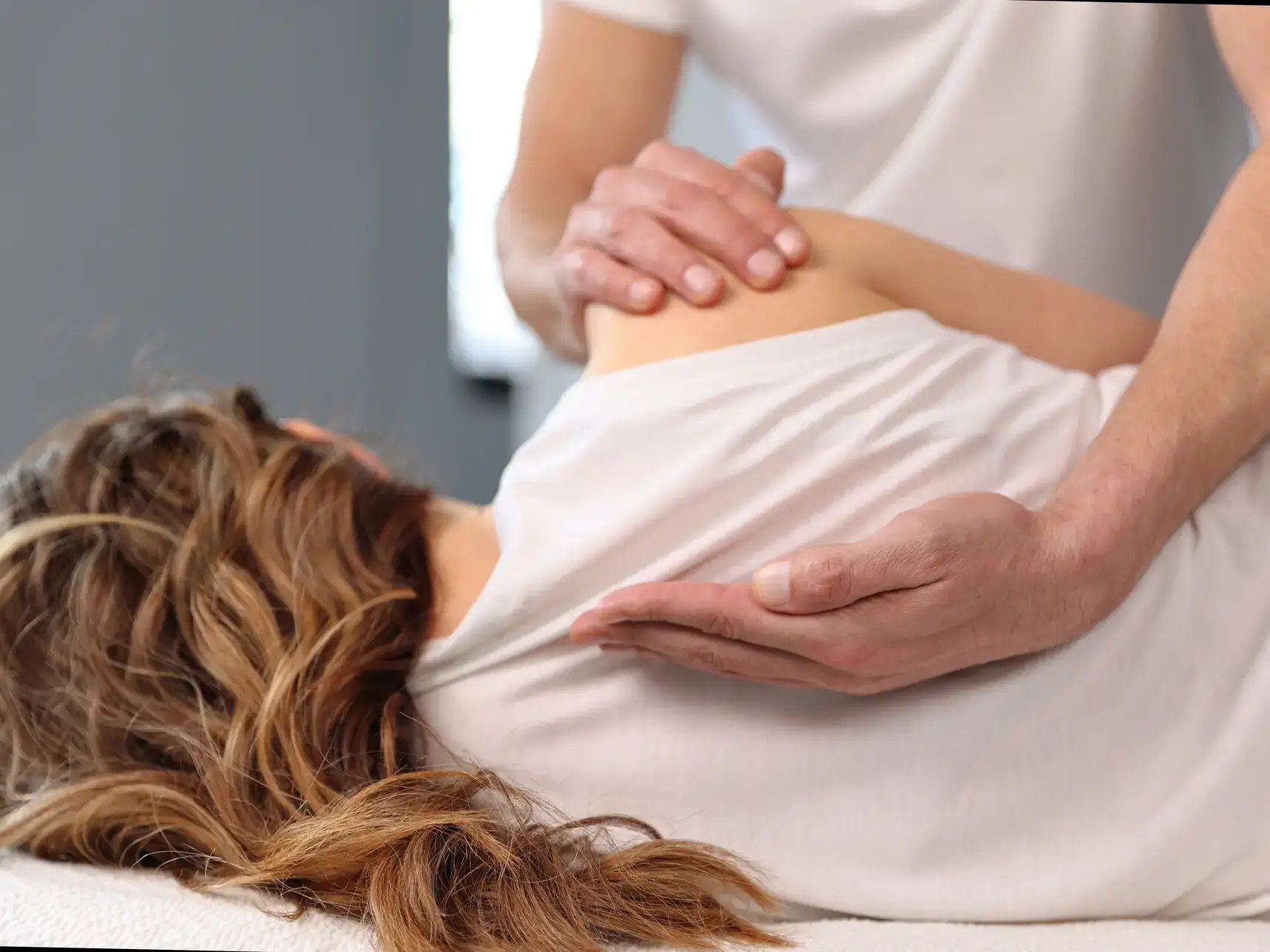 A chiropractor is performing a back adjustment on a patient in a modern clinic. The image highlights the chiropractor's professional posture and the careful, expert care provided to patients in Grand Rapids, MI.