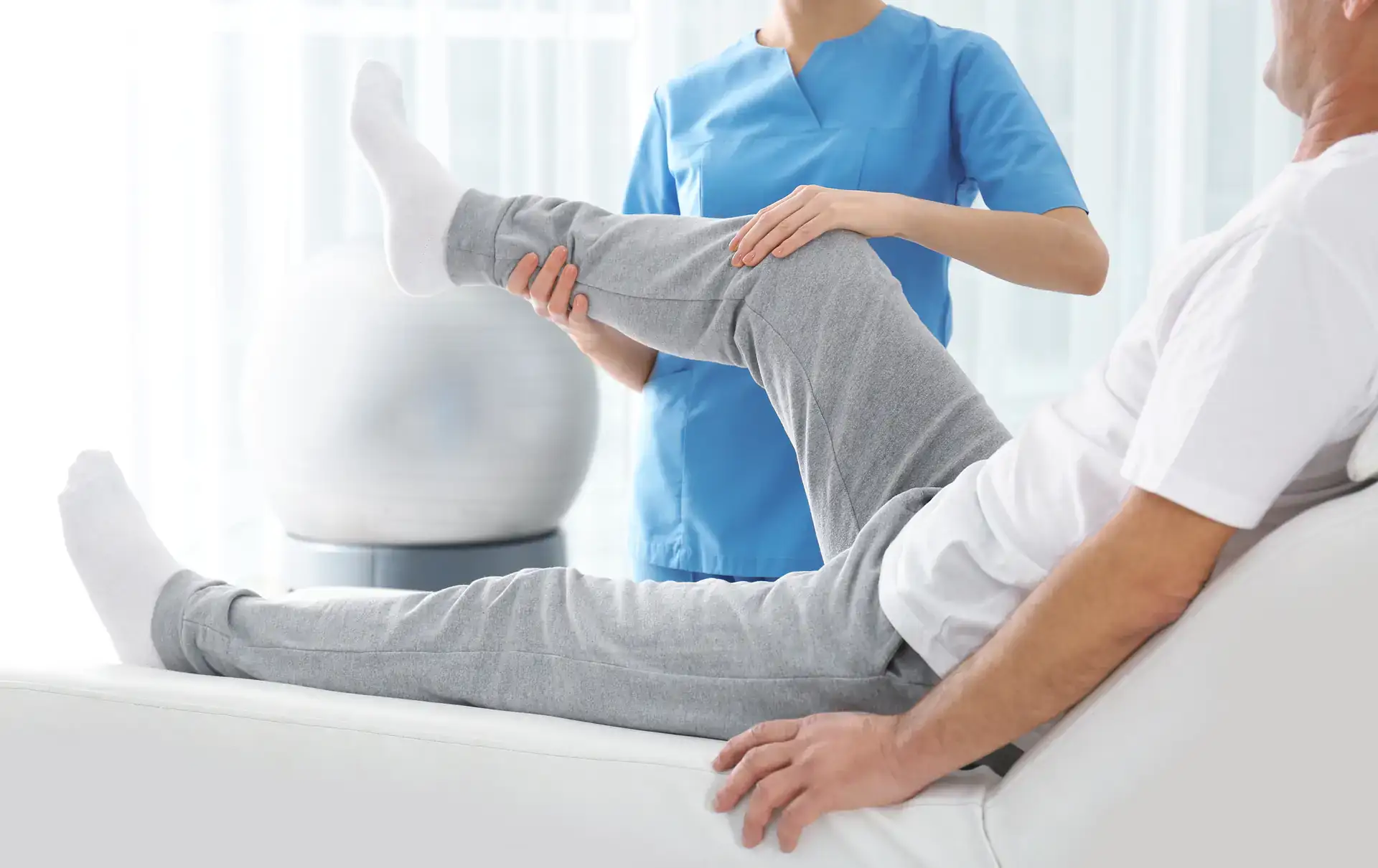 A chiropractor is performing a leg adjustment on a patient in a modern clinic. The focus is on ensuring proper spinal alignment and patient comfort during the treatment in Grand Rapids, MI.