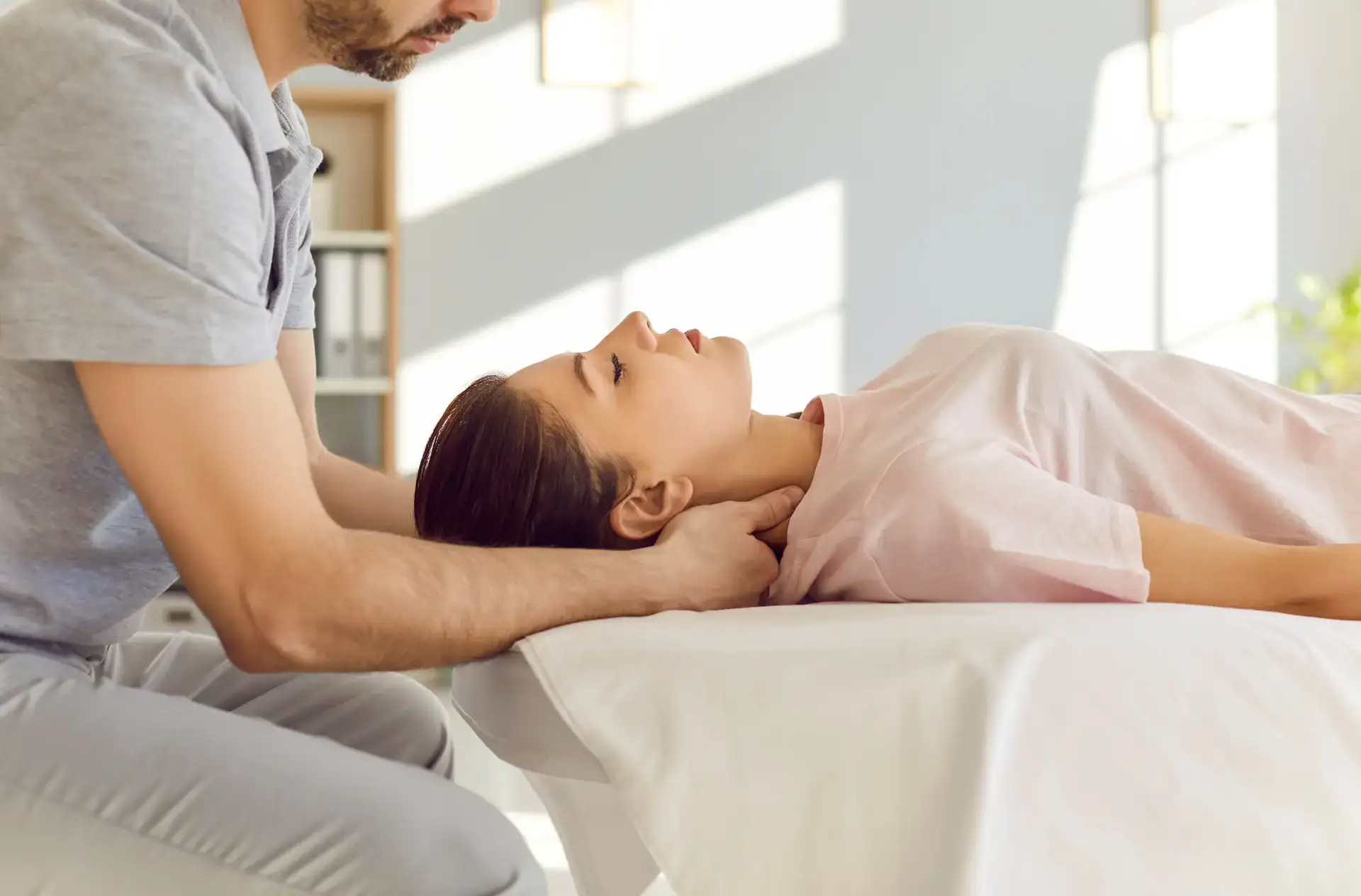 A chiropractor is performing a precise neck adjustment on a patient. This professional and modern clinic setting is located in Grand Rapids, MI.
